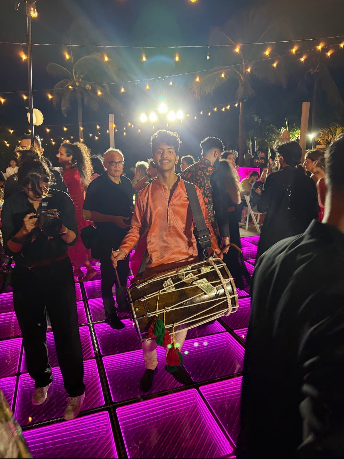 Dhol performance under string lights at an outdoor sangeet